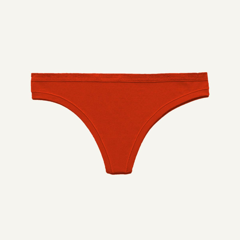 A bright orange-red thong-style underwear bottom shown flat against a light off-white background.