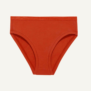 A pair of solid rust-orange cotton bikini bottoms laid flat against a light off-white background.