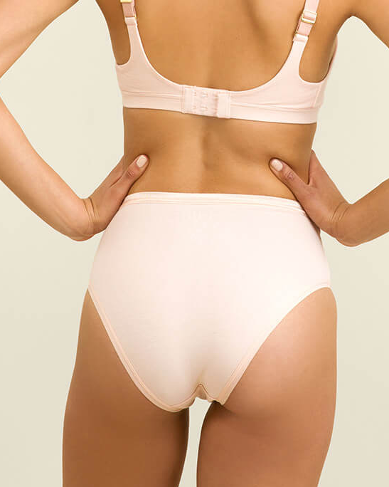 Person wearing a light pink bra and underwear set on a neutral background